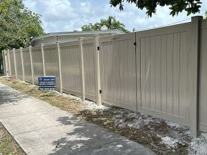Driftwood PVC privacy fence with matching posts and gate installed at a Fort Lauderdale, FL property by Exclusive Custom Fence & Repairs.