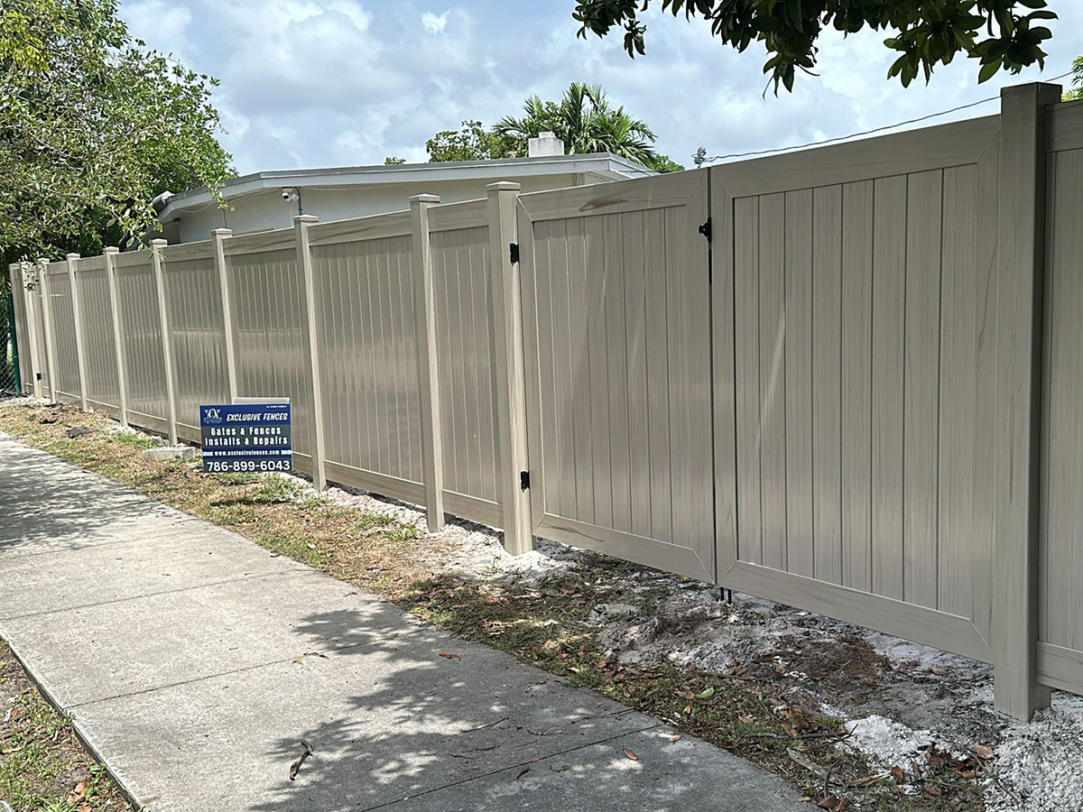 Driftwood PVC privacy fence with matching posts and gate installed at a Fort Lauderdale, FL property by Exclusive Custom Fence & Repairs.